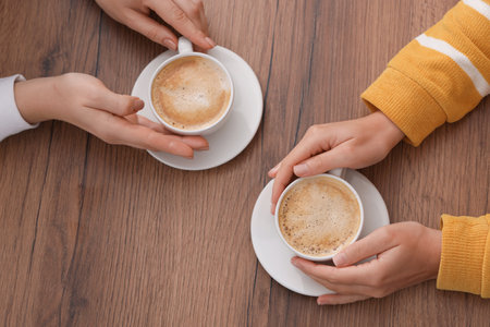Coffee break. People with cups of hot drinks at wooden table, top viewの写真素材