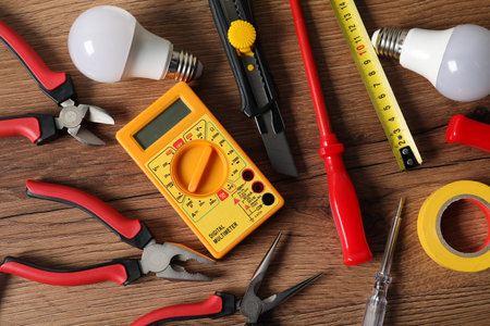 Different electrical tools on wooden table, flat lay