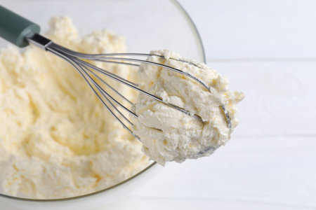 Bowl with whipped cream on white table, closeup