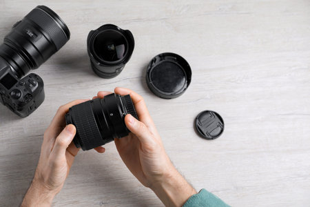 Photographer with camera lens at wooden table, above view. Space for text