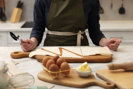 Woman with dough cutter and ingredients at light marble table indoors, selective focus. Making...