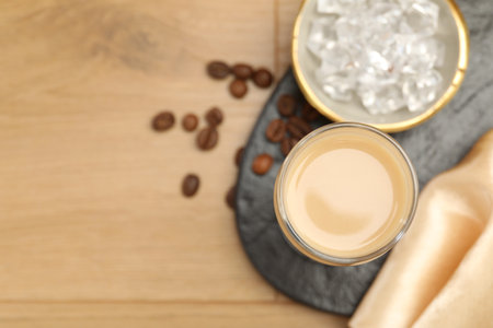 Coffee cream liqueur in glass, ice and beans on wooden table, flat lay. Space for textの写真素材