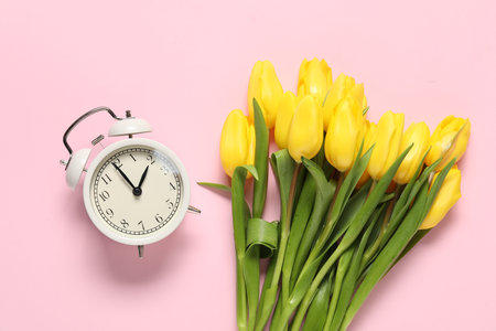 Spring time. Alarm clock and beautiful tulips on pink background, flat layの写真素材