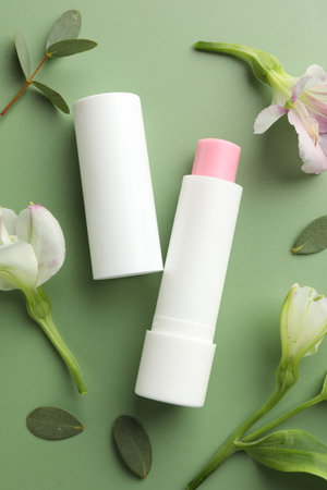 Lip balm and freesia flowers on light green background, flat layの写真素材