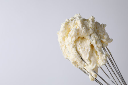 Whisk with whipped cream on white background, closeup. Space for textの写真素材