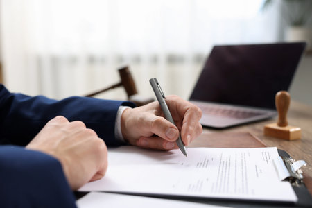 Notary signing document at table in office, closeup