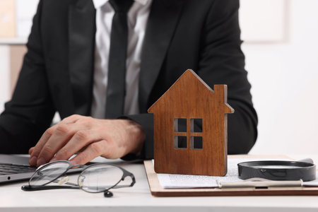 Real estate agent working with laptop at white table with house figure in office, closeup. Home appraisalの写真素材