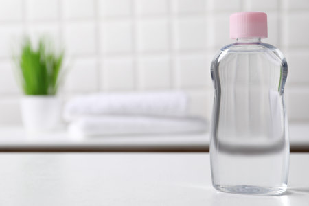 Baby oil in bottle on white table against blurred background. Space for textの写真素材