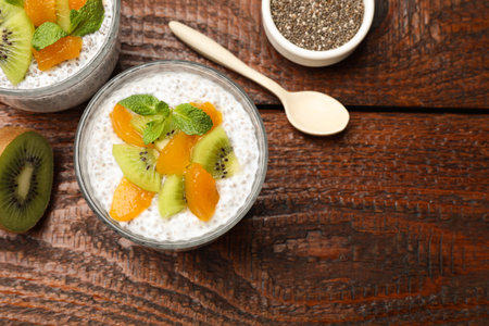 Chia pudding with kiwi, peach and mint in glasses served on wooden table, flat lay. Space for textの写真素材