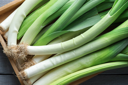 Fresh leeks in crate on grey wooden table, top viewの写真素材