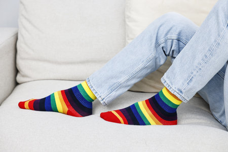Man wearing socks in colors of LGBT flag on sofa, closeupの写真素材