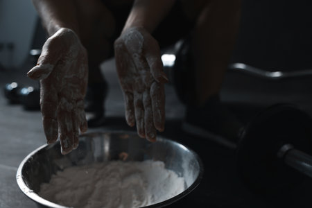 Woman applying talcum powder onto her hands above bowl before training in gym, closeupの写真素材