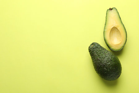 Whole and cut avocados on light green background, flat lay. Space for textの写真素材