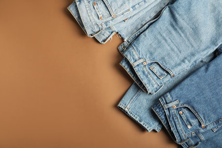Stylish jeans on light brown background, flat lay. Space for textの写真素材