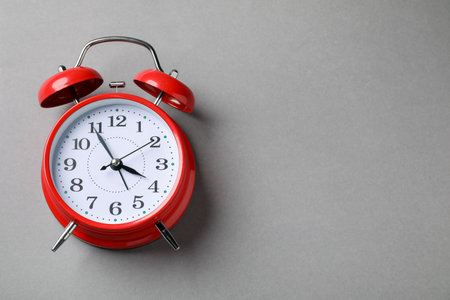 One red alarm clock on light grey background, top view. Space for textの写真素材