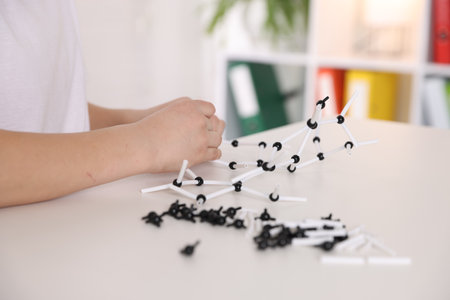 Boy making DNA structure model at desk indoors, closeupの写真素材