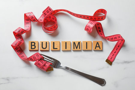 Word Bulimia, fork and measuring tape on white marble table, top viewの写真素材