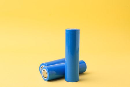 Three AA cell batteries on yellow background, closeupの写真素材