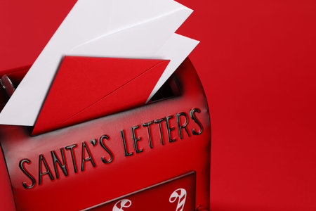 Santa Claus mailbox with letters on red background, closeup with space for text. Christmas tradition