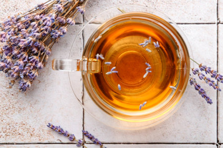 Aromatic lavender tea in glass cup and dry flowers on white tiled table, flat layの写真素材