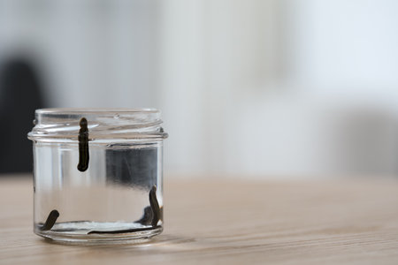 Leeches in glass jar on wooden table, closeup. Space for textの写真素材