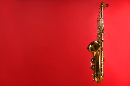 Jazz. One beautiful saxophone on red background.の写真素材