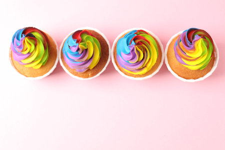 Delicious cupcakes with colorful cream on pink background, flat lay. Space for textの写真素材