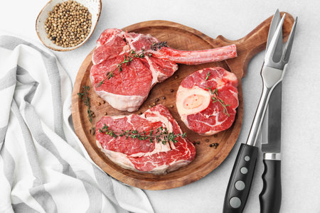 Pieces of raw beef, spices and cutlery on light grey table, flat layの写真素材