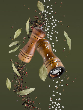 Salt and pepper mills in air on olive color backgroundの写真素材