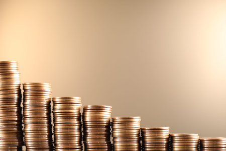 Stacks of coins on beige background, closeup. Space for text
