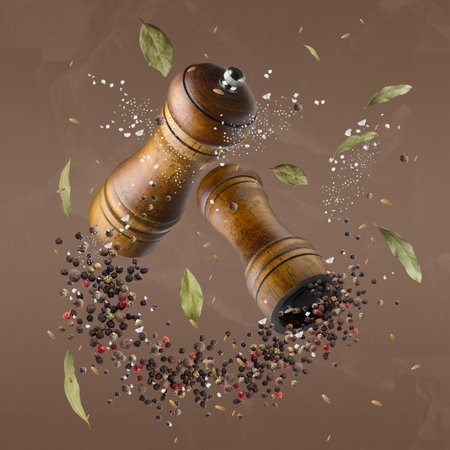 Salt and pepper mills in air on pale brown backgroundの写真素材
