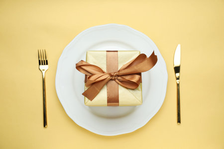 Beautiful table setting with romantic gift on beige background, flat layの写真素材