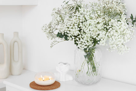 Bouquet of beautiful gypsophila flowers and eucalyptus branches in vase near decorative elements on table indoorsの写真素材