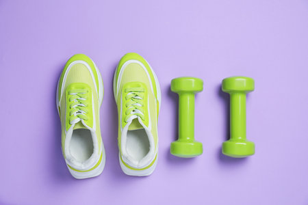 Sneakers and dumbbells on violet background, flat lay. Sports equipmentの写真素材