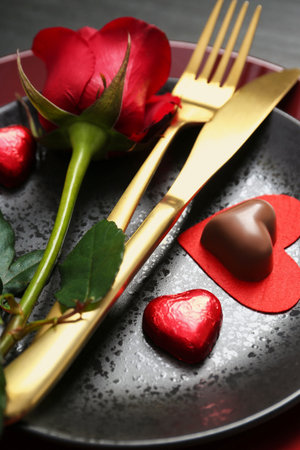 Romantic place setting with rose and plates on table, closeup. Valentine's day celebrationの写真素材