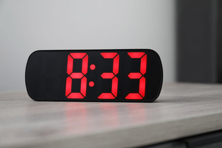 Digital alarm clock showing 8:33 o'clock on bedside table indoors