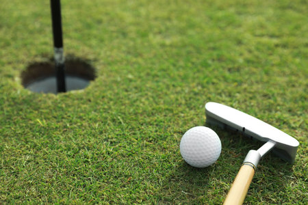 Golf ball and club near hole on green courseの写真素材