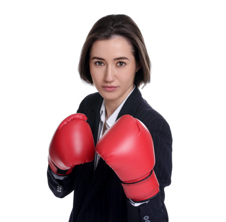 Competition. Businesswoman in suit wearing boxing gloves on white backgroundの写真素材