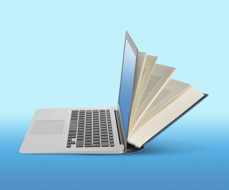 Open book and laptop on light blue gradient background. E-learning, internet library, online webinarの写真素材