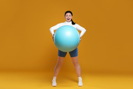 Plus size woman in gym clothes with fitness ballの写真素材