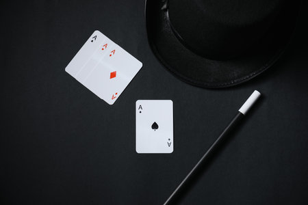 Playing cards, hat and magic wand on black background, top viewの写真素材