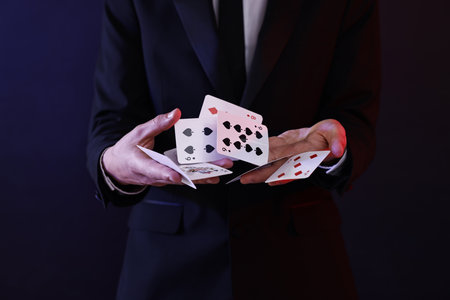 Illusionist showing trick with playing cards on dark background, closeupの写真素材