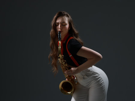 Professional musician playing saxophone on grey background. Space for textの写真素材