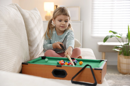 Cute little girl playing billiards at homeの写真素材