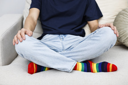 Man wearing socks in colors of LGBT flag on sofa, closeupの写真素材