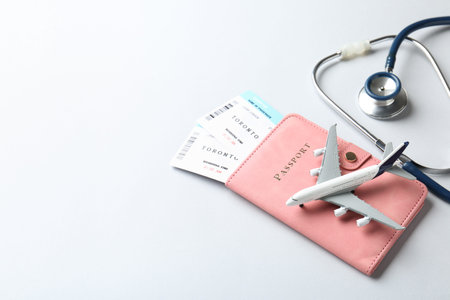 Medical tourism. Stethoscope, plane model, passport and flight tickets on light blue background. Space for textの写真素材