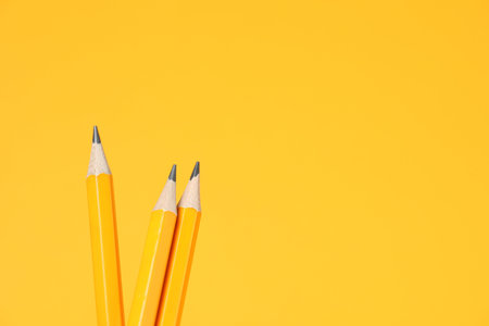 Many graphite pencils on orange background, closeup.