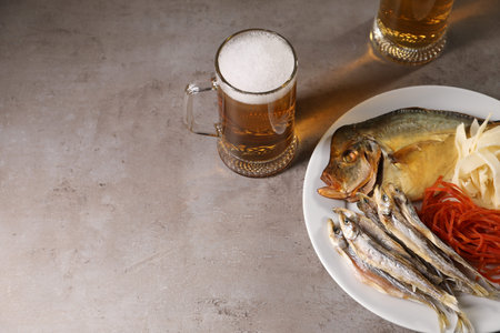 Different dried fish snacks and beer on gray table, above view. Space for textの写真素材