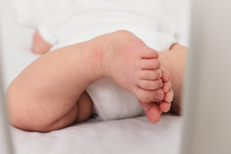 Cute little baby in crib at home, closeup of feetの写真素材