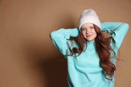 Beautiful teenage girl with freckles in hat on brown background, space for textの写真素材